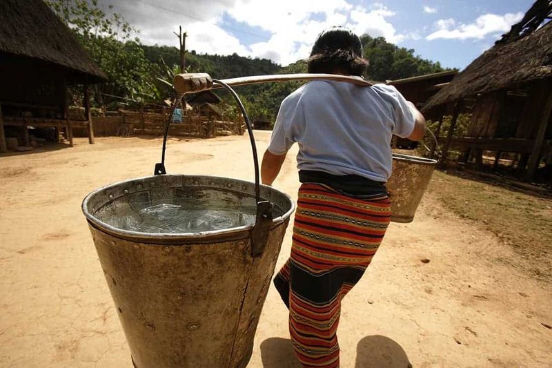 Woman carrying two buckets full of water. #status_of_drinking_water_in_Nepal